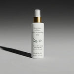 White bottle of FW Beauty Rosemary & Clove Hair Hydrating Mist on a gray background