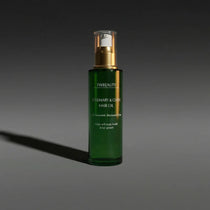 Green hair oil bottle with gold cap on a dark gray background