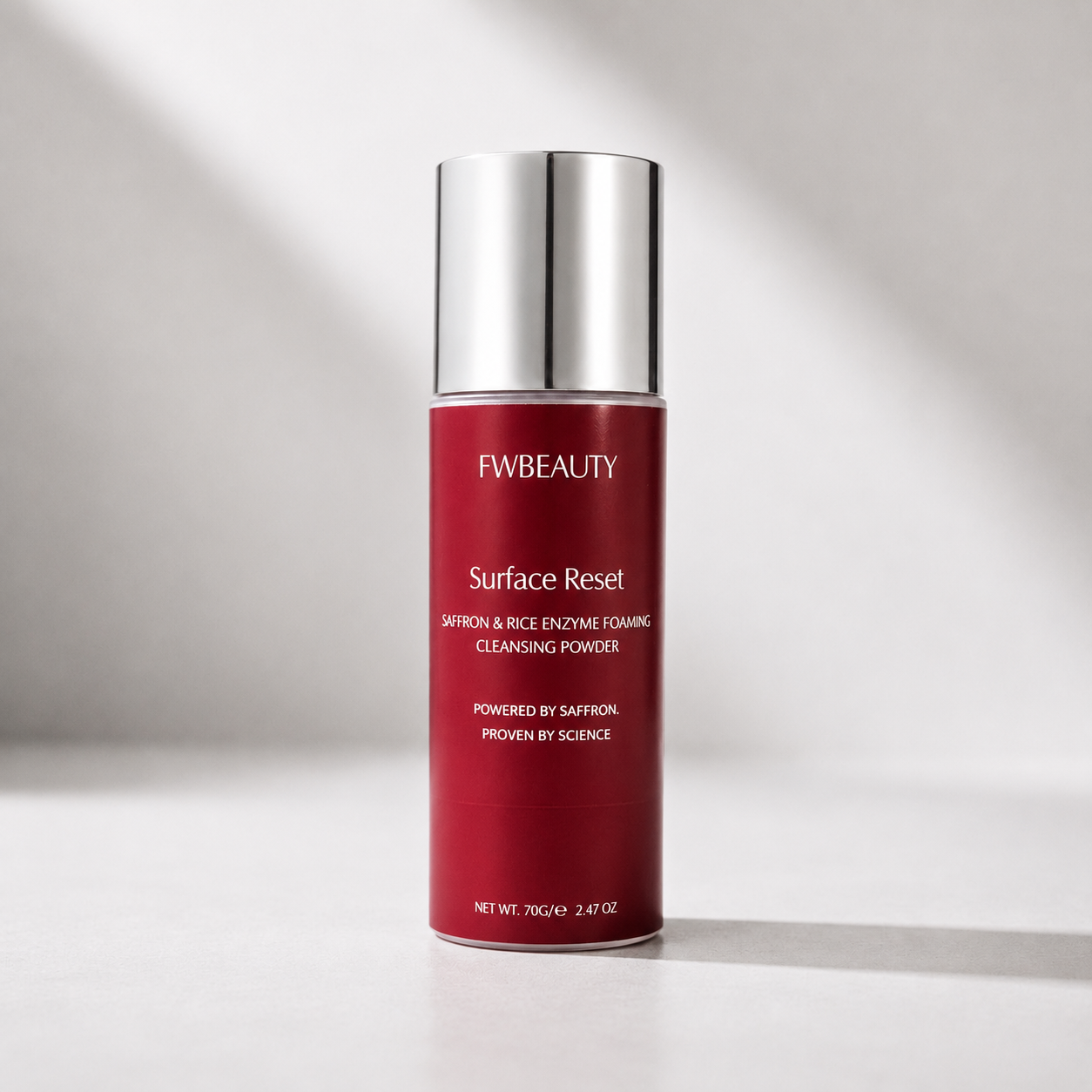 FWBEAUTY Surface Reset Cleansing Powder in a red cylindrical bottle with a reflective silver cap, set against a light gray background with soft diagonal shadows.